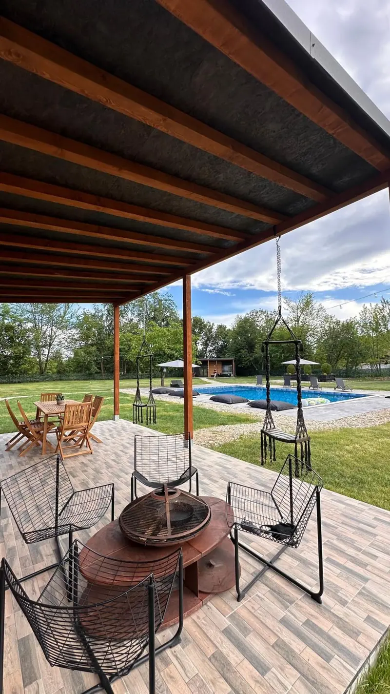Terasa cu vatră de foc, leagăn și piscina în fundal